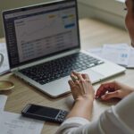 A business owner using financial management software on a laptop surrounded by 1778011334