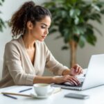 Empreendedora analisando planilha de contas a pagar e receber em computador, representando controle financeiro e gestão de fluxo de caixa